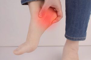 Person holding their heel in pain before plantar fasciitis treatment